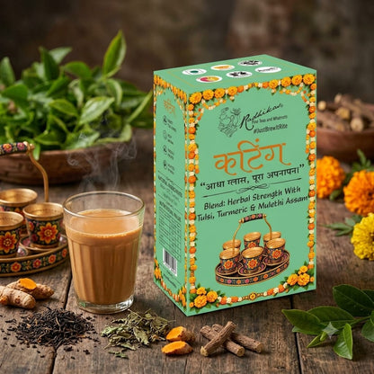 A box of Mallickarot Herbal Tea Blend 'Kattega' is displayed on a rustic wooden table alongside a glass of brewed tea, loose herbs, turmeric, ginger, and fresh green leaves.