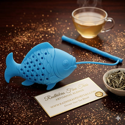 Blue fish-shaped tea infuser on a wooden surface with a cup of tea and a bowl of tea leaves.