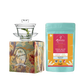 A glass gaiwan set with a saucer and a lid, accompanied by a pack of Radhikas Fine Teas Assam Masala Tea. The gaiwan has a floral design on the packaging.
