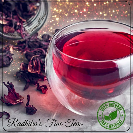 Glass of red tea with dried hibiscus flowers and 'Radhika's Fine Teas' branding.