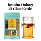 A contemporary glass kettle with a porcelain infuser next to a package of Radiance China Jasmine Oolong Tea by Radhikas Fine Teas.