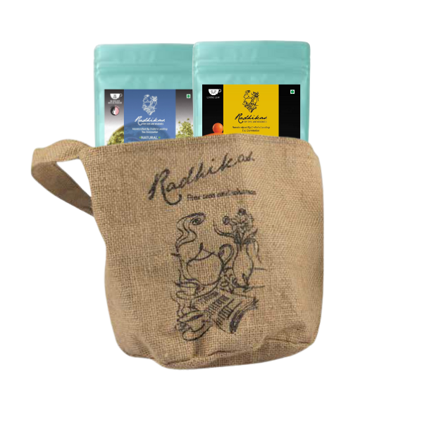 Two ziplocked pouches of Radhikas Fine Teas, one with a matcha green label and the other with a butterfly blue label, placed inside a beige jute bag with an illustration of a tea pot and leaves.