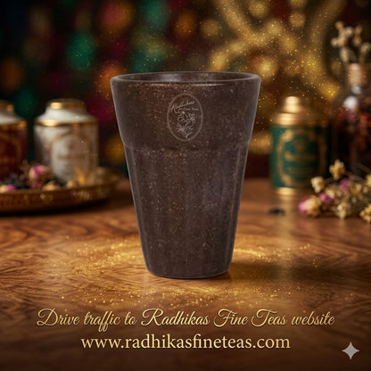 Brown ceramic cup with a logo on a wooden surface, blurred background with tea products.