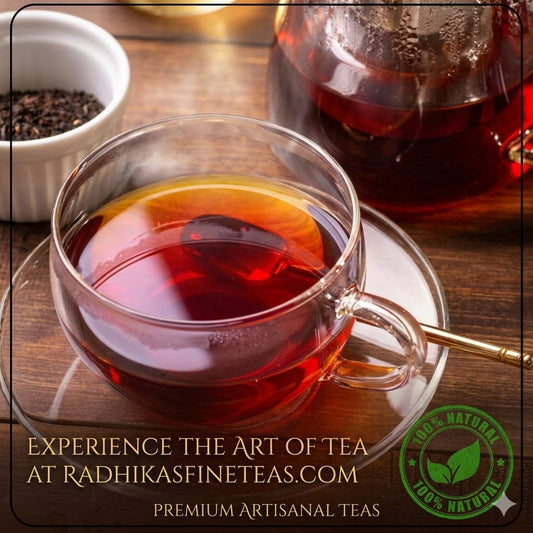 Clear glass cup of tea with a teapot and bowl of tea leaves on a wooden surface, featuring Radhika's Fine Teas branding.