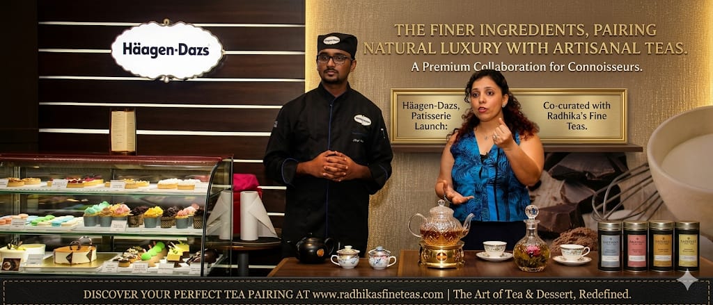 Two people standing behind a counter with various items, including a display of desserts and a teapot, with a focus on a collaboration between Häagen-Dazs and Radhika's Fine Teas.