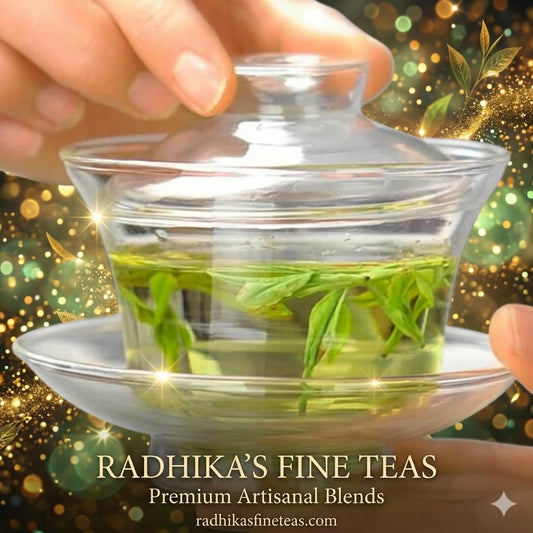 Clear glass teapot with green tea leaves held by a hand, Radhika's Fine Teas branding visible.
