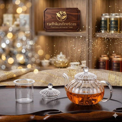 Glass teapot with tea on a wooden table, 'radhikasfineteas' brand visible