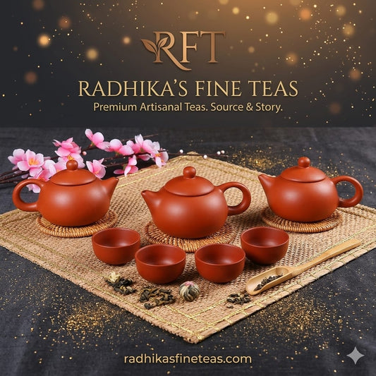 Red teapots and cups on a woven mat with 'Radhika's Fine Teas' branding.